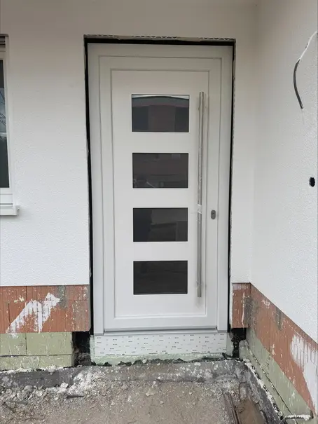 Moderne weiße Haustür mit Glaselementen und Stangengriff nach dem Einbau