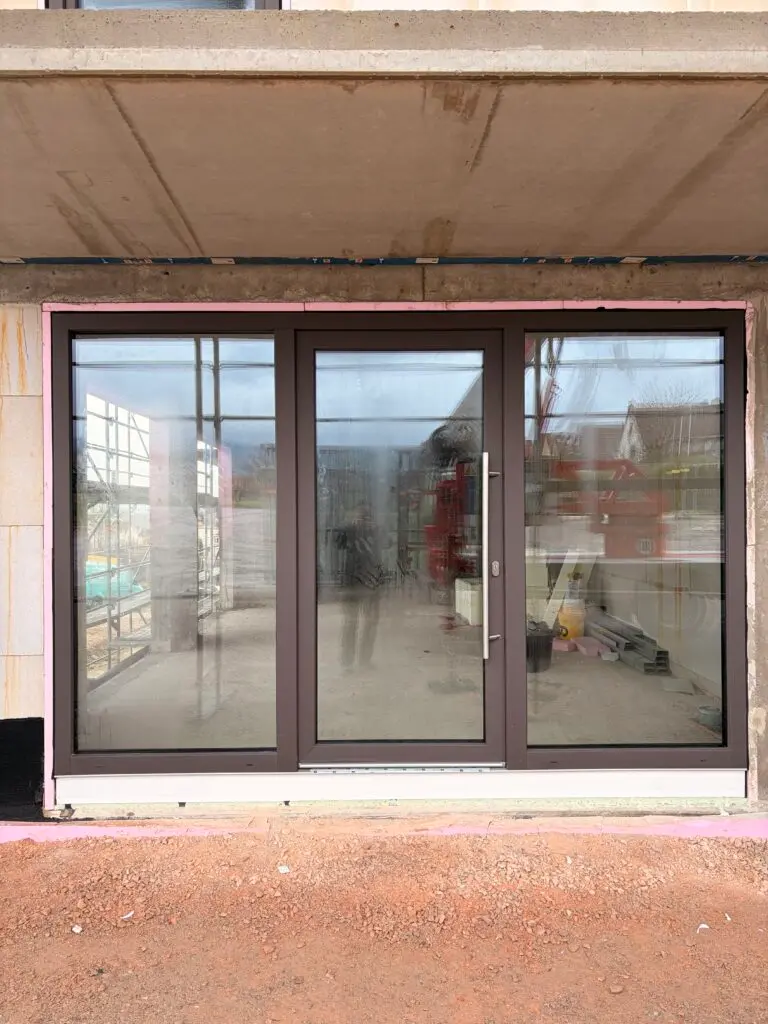 Neu eingebaute Hebeschiebetür mit dunklem Rahmen im Rohbau